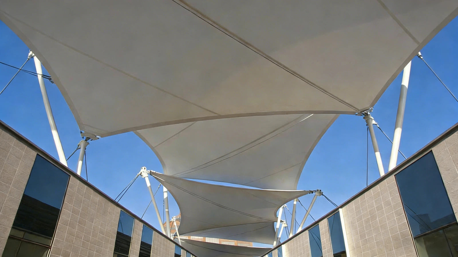 Tensile shade sails tensioned between commercial building facades