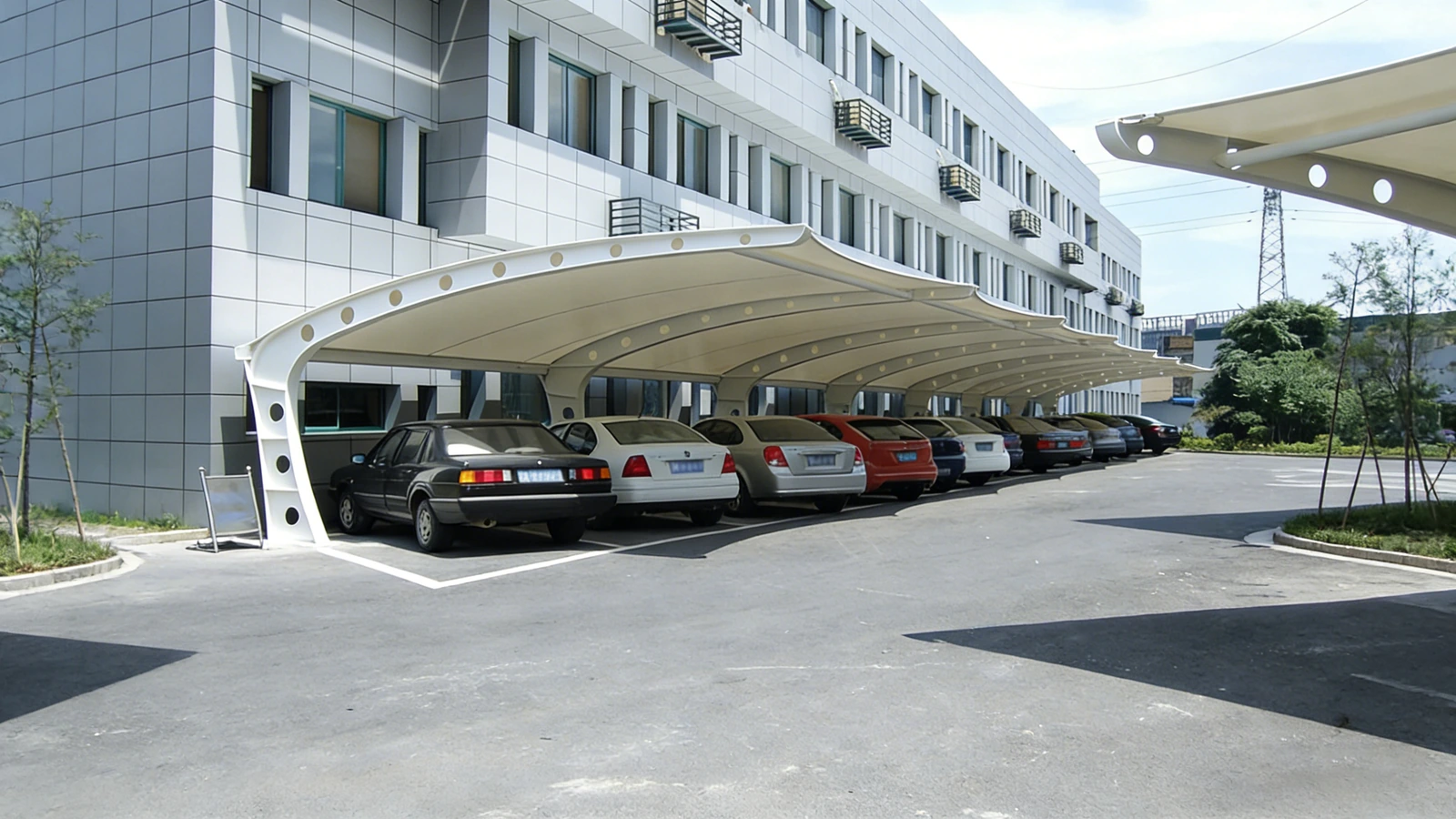 Cantilever membrane carport along a building facade