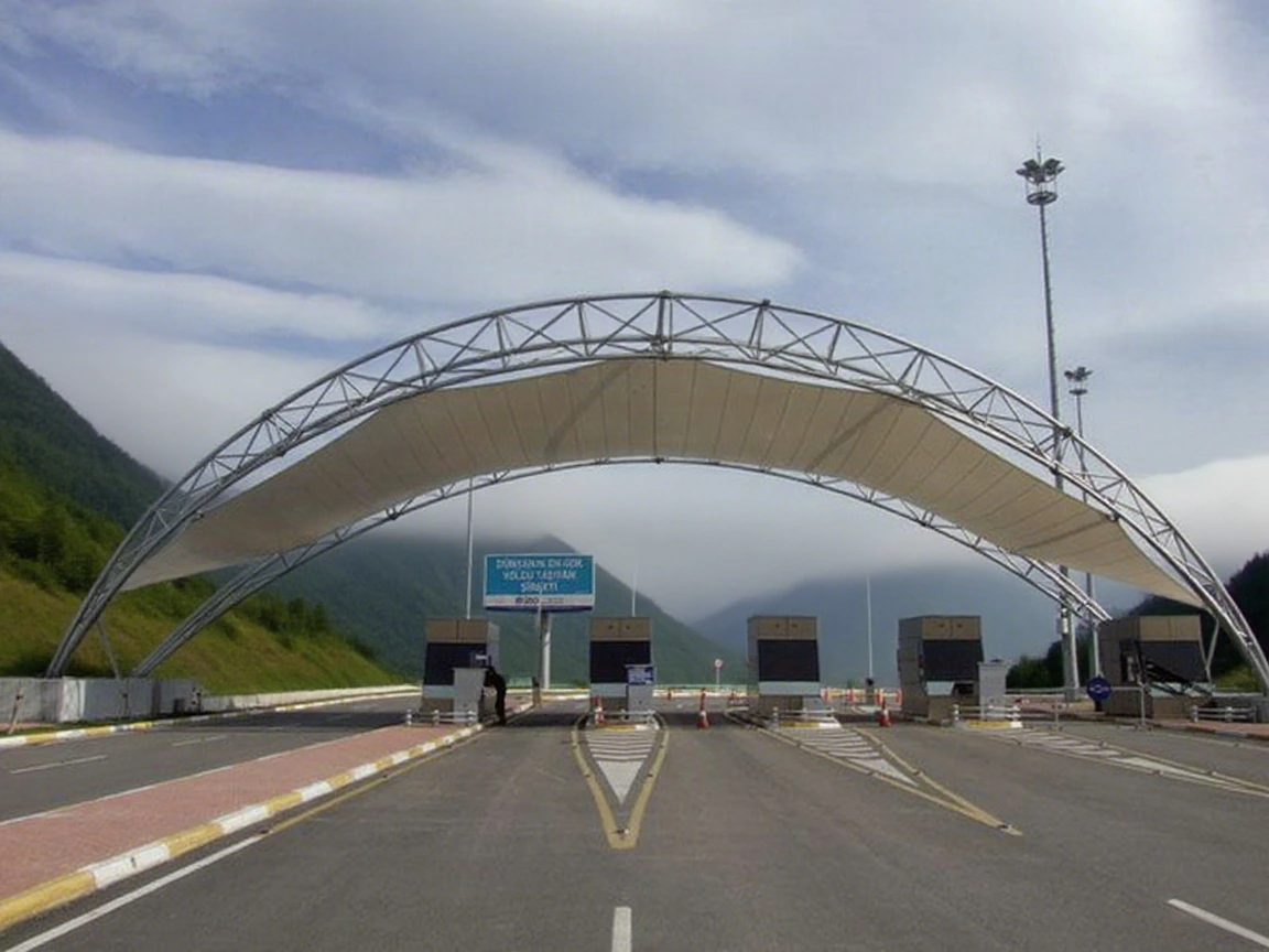 Steel arch supporting a tensile membrane roof over toll lanes
